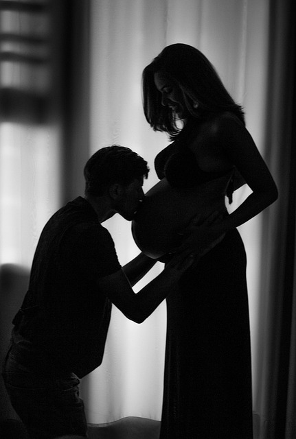 silhouette of man kissing woman's belly