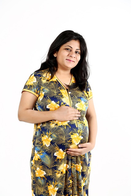 pregnant woman in yellow flower dress holding her belly